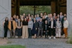 A group photo of thirty people gathered in front of a barn