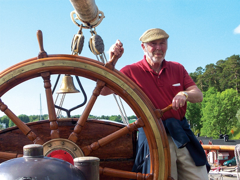 Jim Simons holds the wheel of a sailboat.