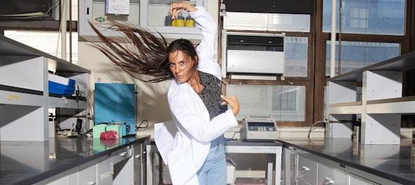 Woman in lab coat dancing with her hair flipping in the air