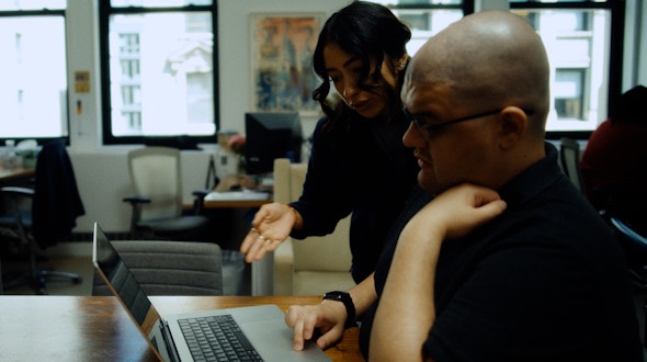 Two people working on the computer.