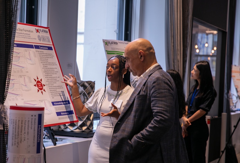 Woman explains poster to a man in a suit.